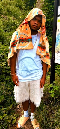 a man in shorts and a hoodie standing in a wooded area